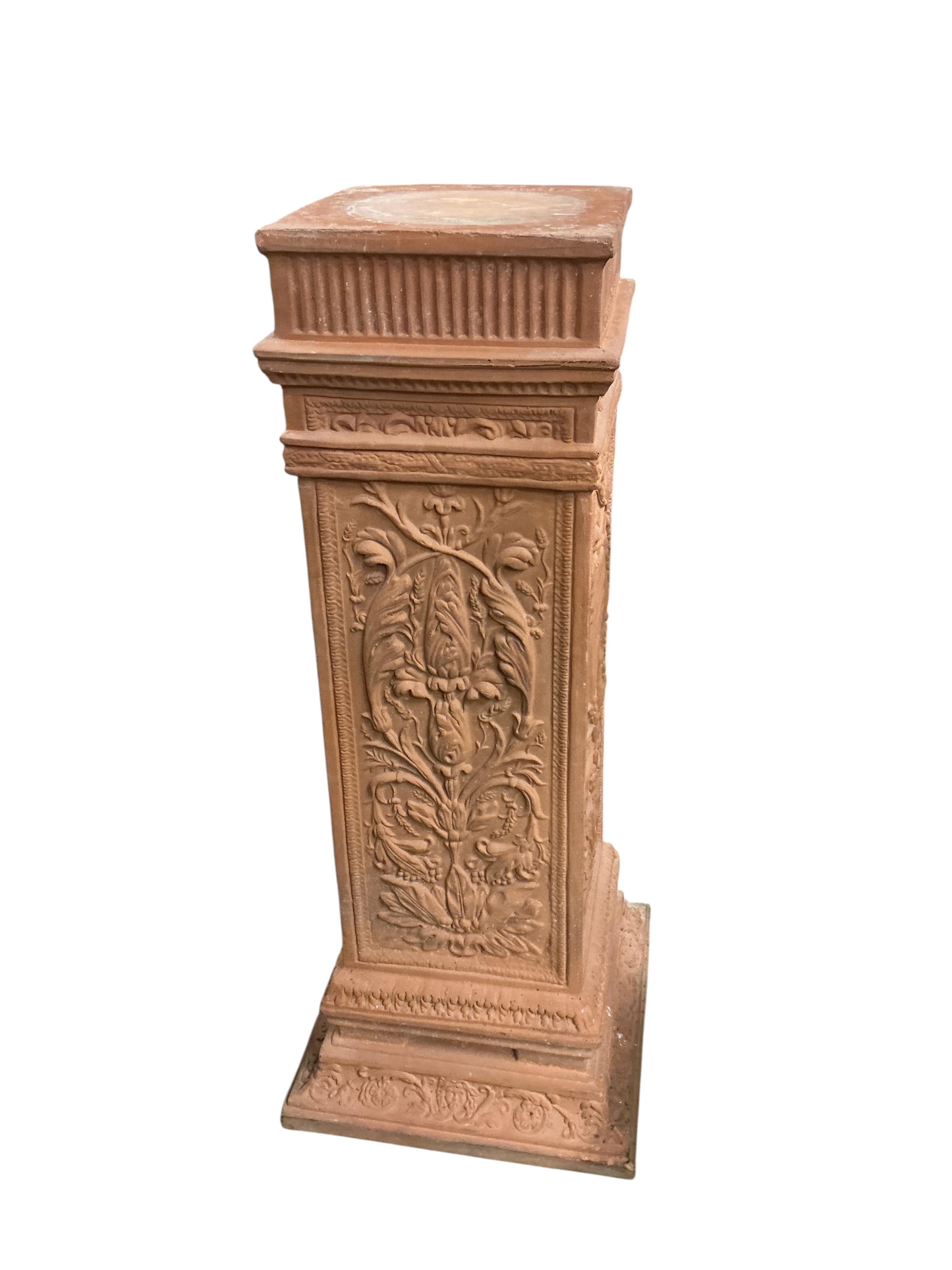 A pair of terracotta pedestals, decorated with panels of scrolling foliage, width 45cm, height 109cm